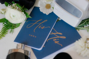 two vow blue vowbooks labeled "His Vows" on a surface.