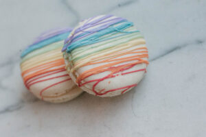 white macaroons with stripes of icing in the colors of the rainbow.