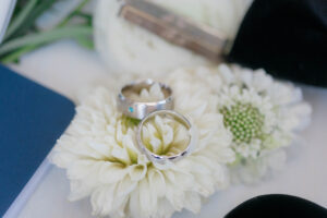 close up of two platitinum mens wedding bands resting on a white flower.